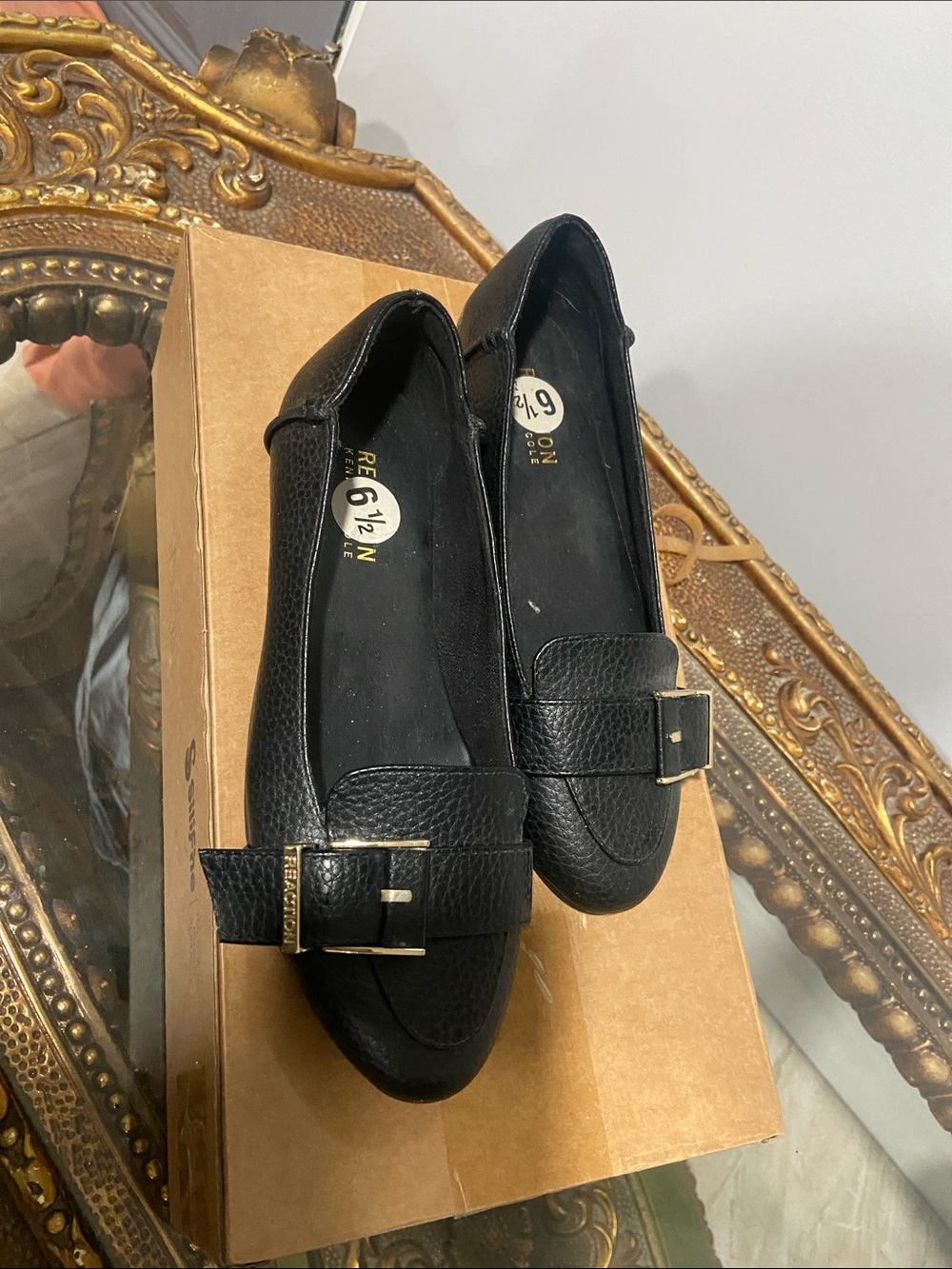 Kenneth Cole Viv" loafers, black upper and a prominent gold-tone buckle detail.